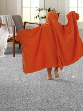 Image presents OAK & STONE FLOORS Shaw carpet flooring, available in Oregon and Washington, with a young child playing in bare feet on carpet to visualize the concept that carpet can reduce you home energy bill.