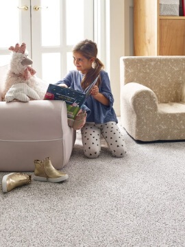 Image presents OAK & STONE FLOORS Shaw carpet flooring, available in Oregon and Washington, with a young child playing to visualize the concept that carpet is comfortable and safe for playing children and fragile elderly people.