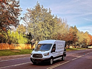 Image presents the Oak & Stone Floors Shop-At-Home mobile van during delivery time, and that's not pizza we're hauling, that van is bringing stylin' flooring samples to your front door.